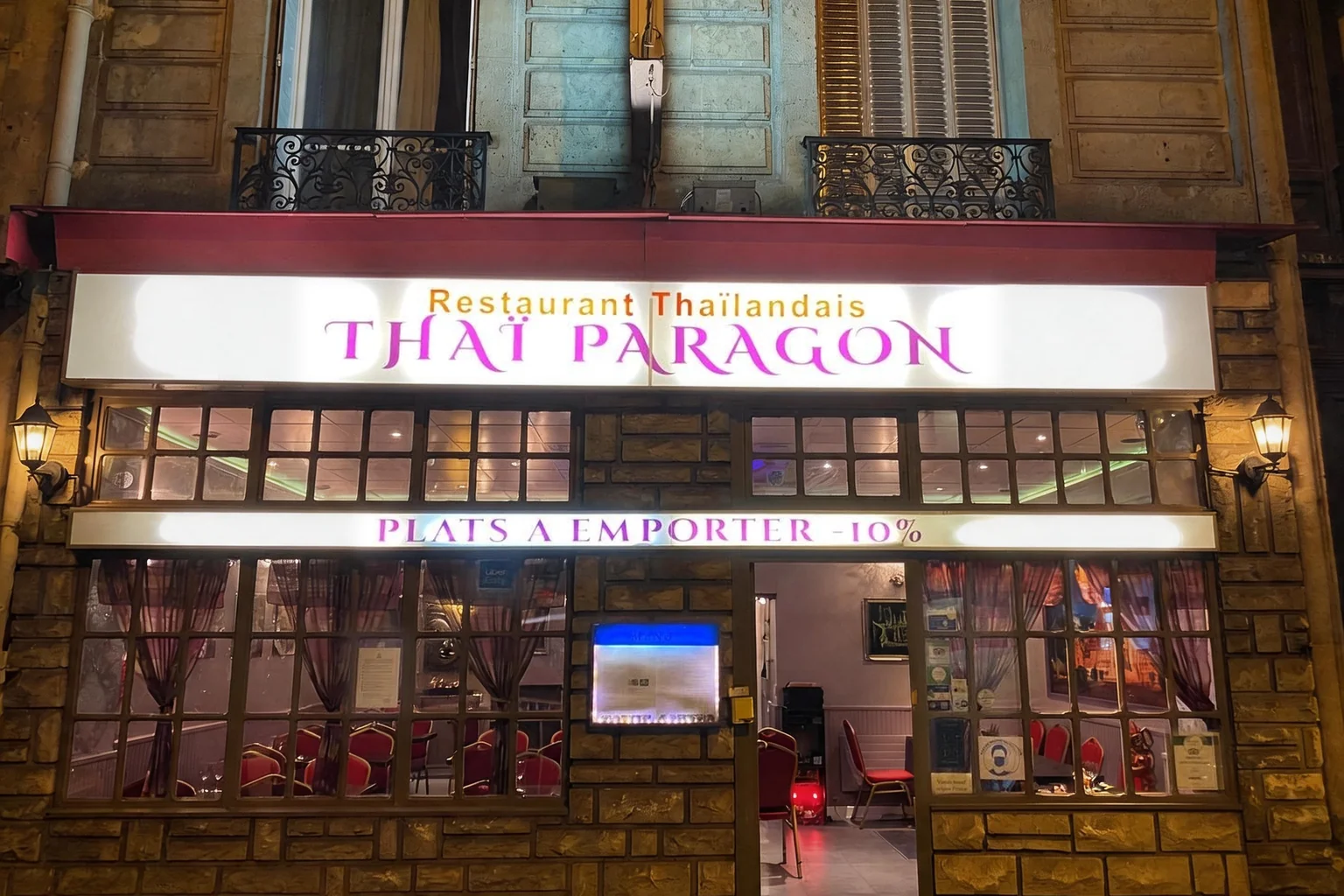 Thaï Paragon shopfront in the evening, illuminated sign and lit windows