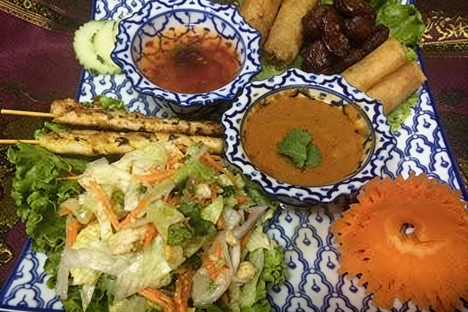 Assortment of starters on a blue and white platter, sauce bowls, on a purple tablecloth